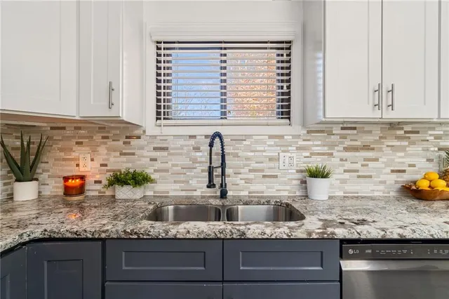 a kitchen with granite countertop a sink and potted white stainless steel appliances