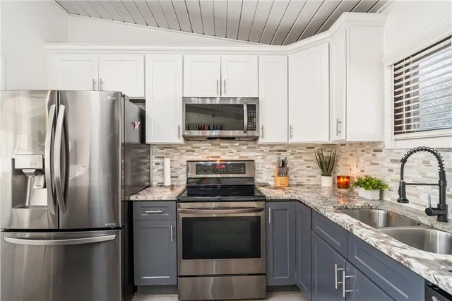 a kitchen with refrigerator a microwave a sink and cabinets