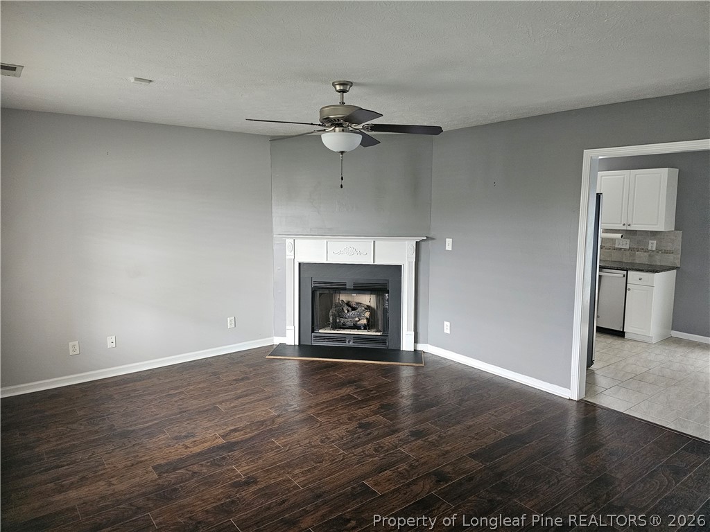 5708 Spreading Branch Road Hope Mills, NC 28348 - Photo 3 of 21 an empty room with wooden floor a ceiling fan a fireplace and windows