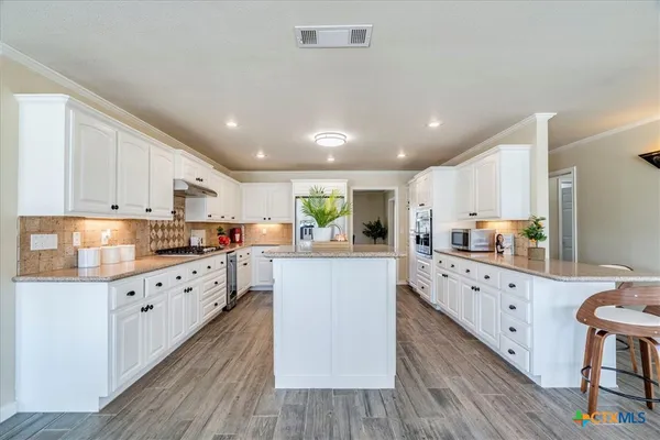 a kitchen with counter top space a sink wooden floor and stainless steel appliances