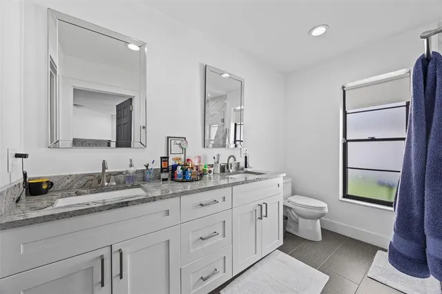 a bathroom with a toilet a double vanity sink and a mirror