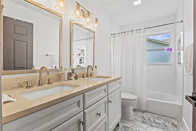 a bathroom with a granite countertop sink a toilet and shower