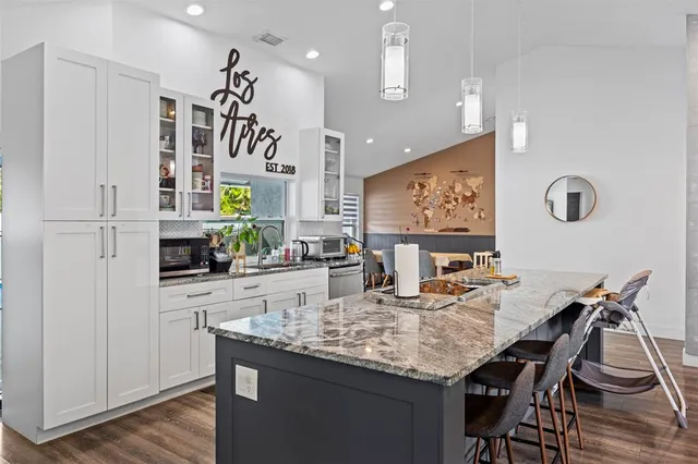 a kitchen with granite countertop white cabinets and chairs
