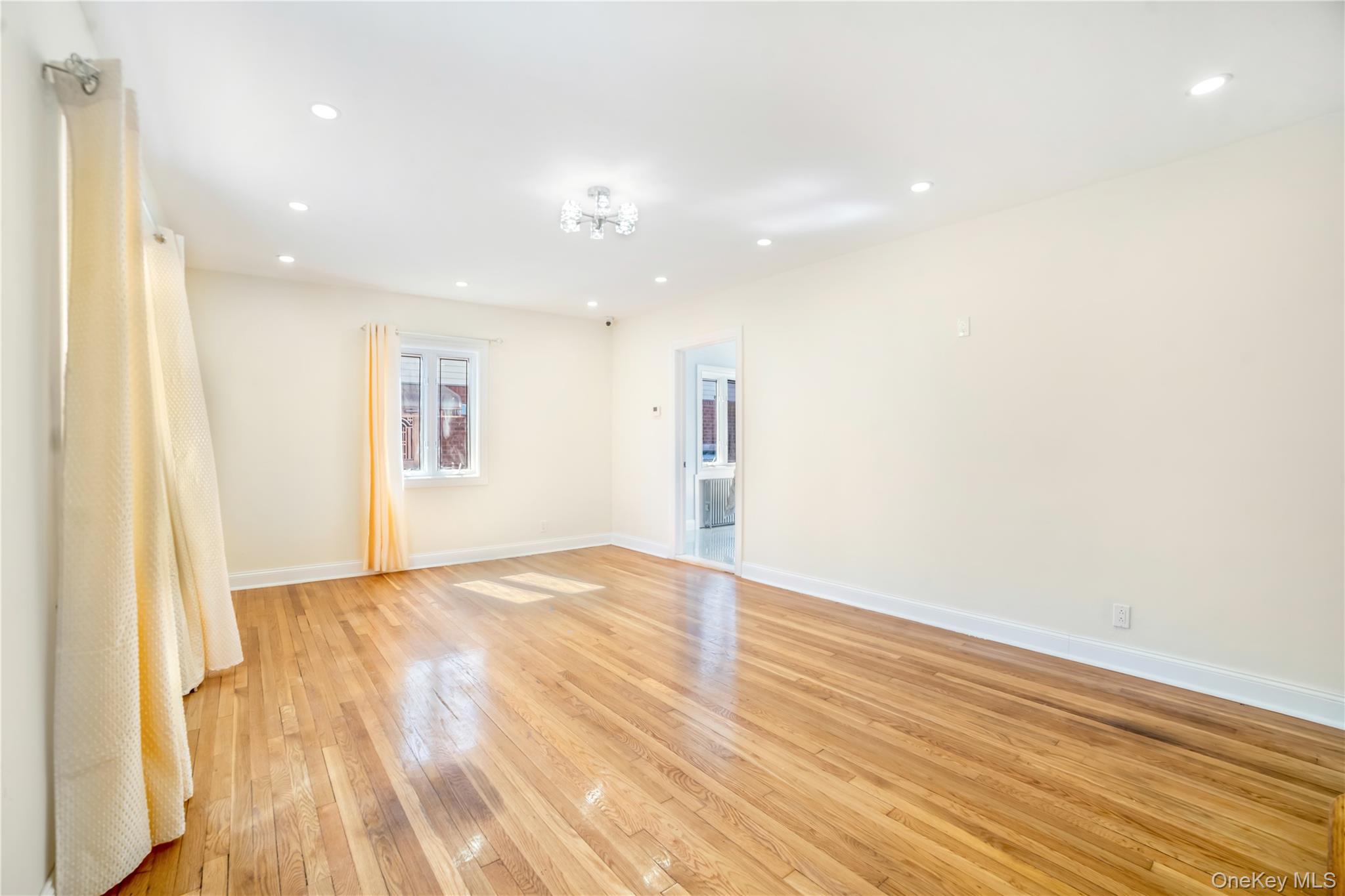 81-28 252nd Street Queens, NY 11426 - Photo 2 of 21 a view of an empty room with wooden floor and a window