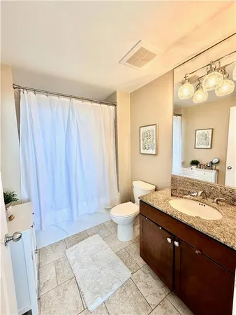 a bathroom with a granite countertop sink toilet and shower