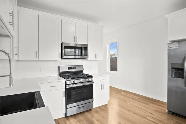 a kitchen with granite countertop white cabinets and stainless steel appliances