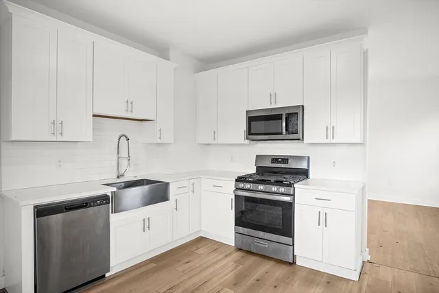 a kitchen with white cabinets and stainless steel appliances