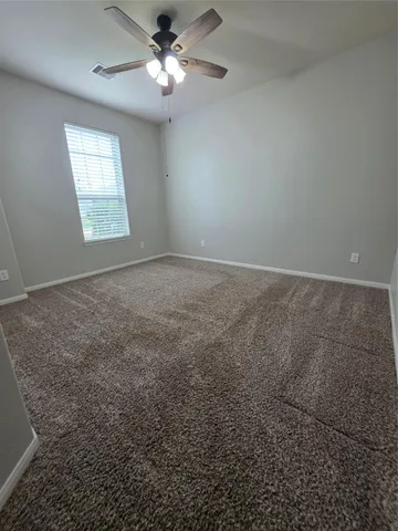 an empty room with windows and fan