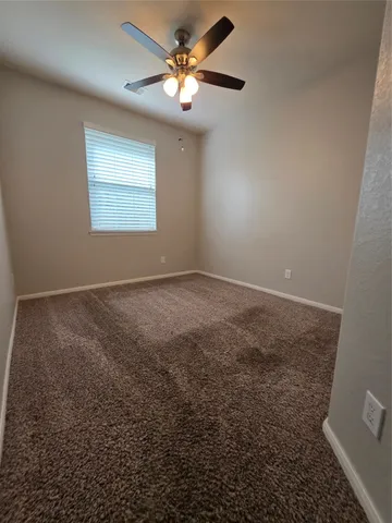 an empty room with a window and a ceiling fan