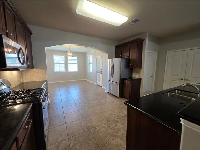 a kitchen with granite countertop a refrigerator stove and sink