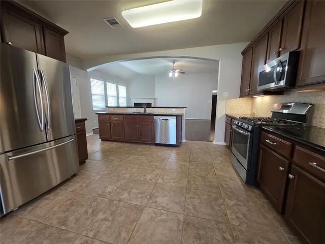 a kitchen with stainless steel appliances granite countertop a refrigerator a stove a sink a washer dryer and a cabinets