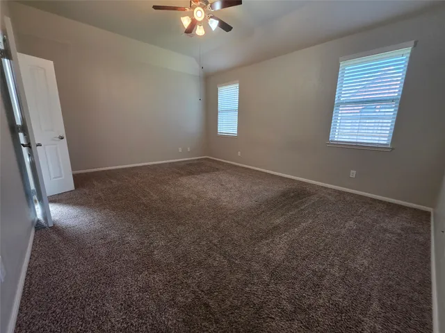 an empty room with windows and chandelier fan