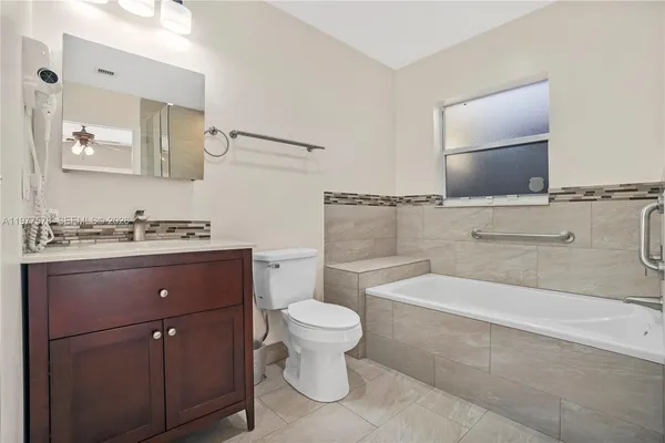 a bathroom with a granite countertop sink a toilet and mirror