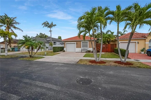 a view of a house with a yard and palm trees