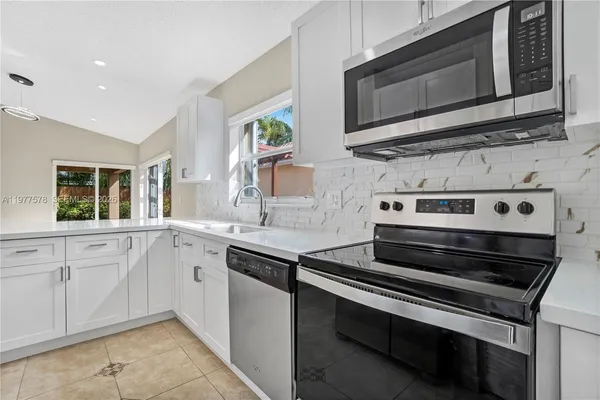 a kitchen with stainless steel appliances a stove microwave and sink