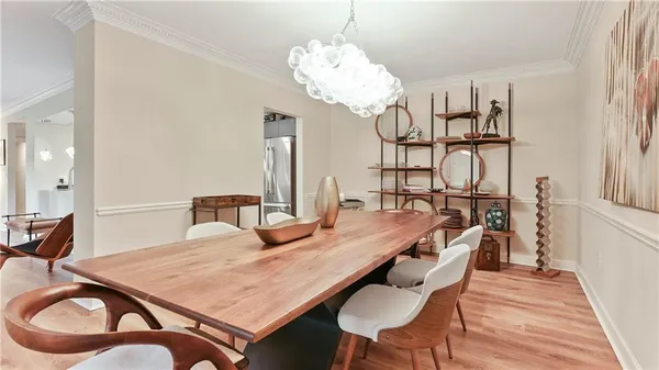 a dining room with wooden floor a chandelier a wooden table and chairs