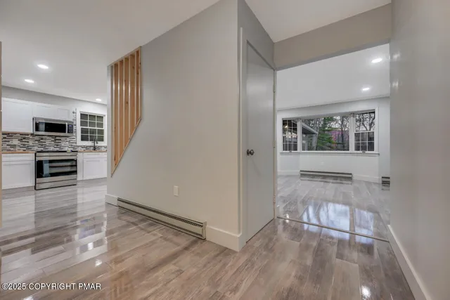 a view of an empty room with wooden floor and a window