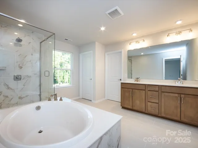 a spacious bathroom with a tub sink shower and mirror