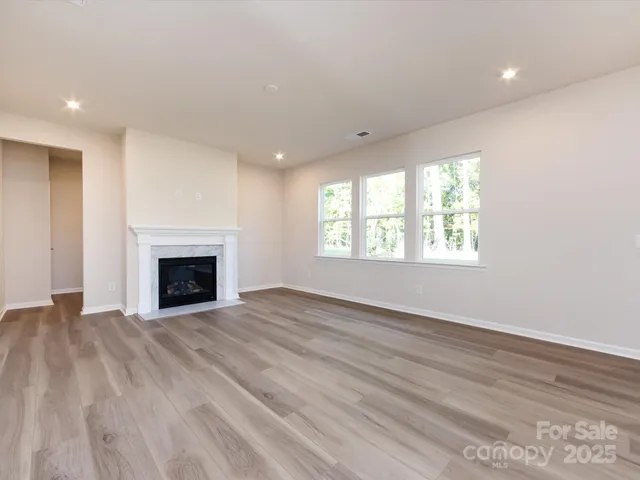 an empty room with windows and fireplace