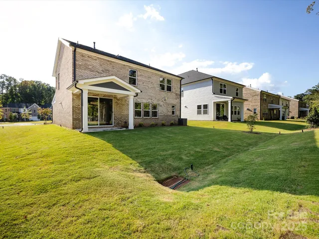 a view of a white house with a big yard and large trees