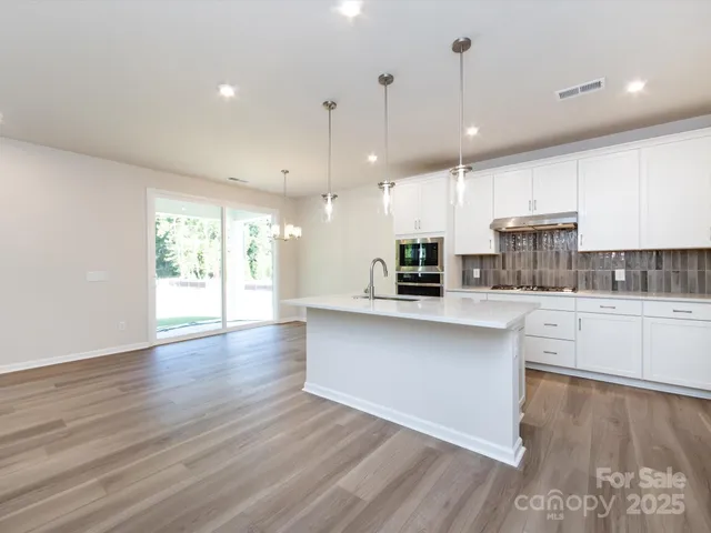 a large kitchen with stainless steel appliances granite countertop a large window a oven and a sink