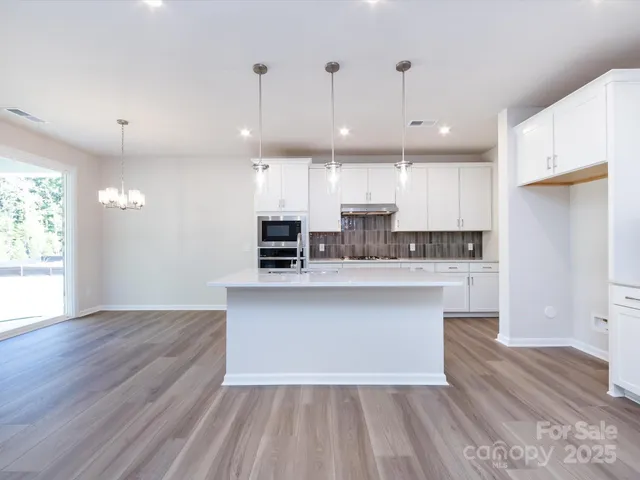a large kitchen with cabinets wooden floor and stainless steel appliances
