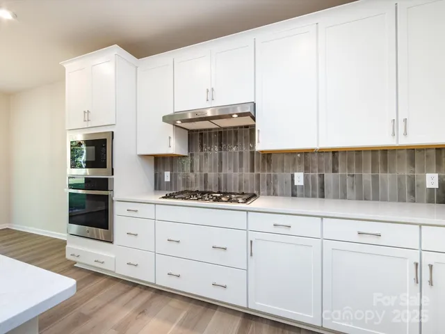 a kitchen with granite countertop white cabinets and white appliances