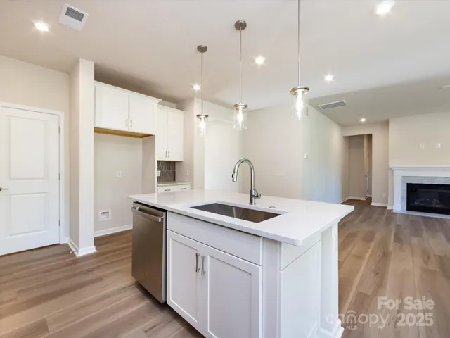 a kitchen with a sink chandelier and wooden floor