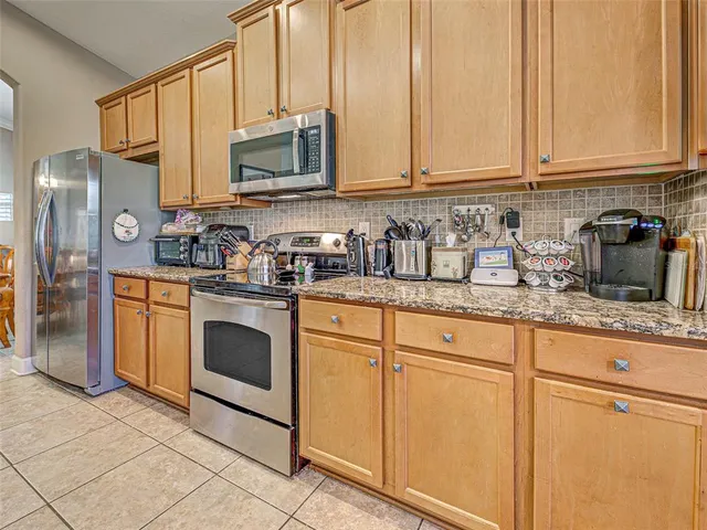 a kitchen with stainless steel appliances granite countertop a refrigerator and a stove top oven