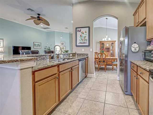 a kitchen with stainless steel appliances kitchen island granite countertop a refrigerator a stove a microwave oven and a dining table with wooden floor