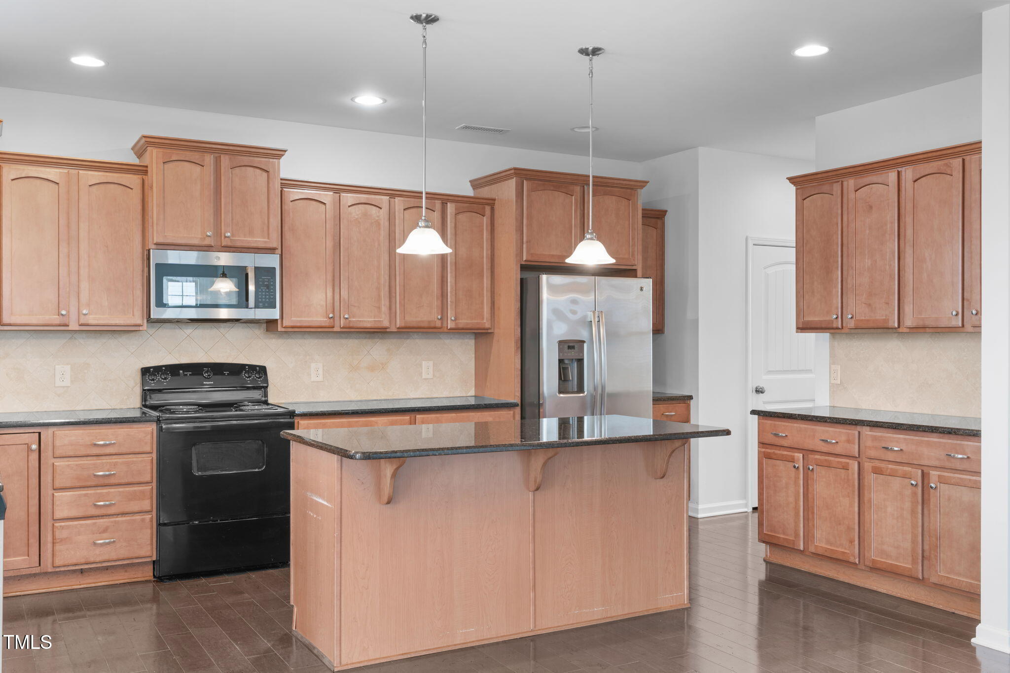4139 Davis Meadow Street Raleigh, NC 27616 - Photo 15 of 43 a kitchen with kitchen island granite countertop a stove a sink and white cabinets