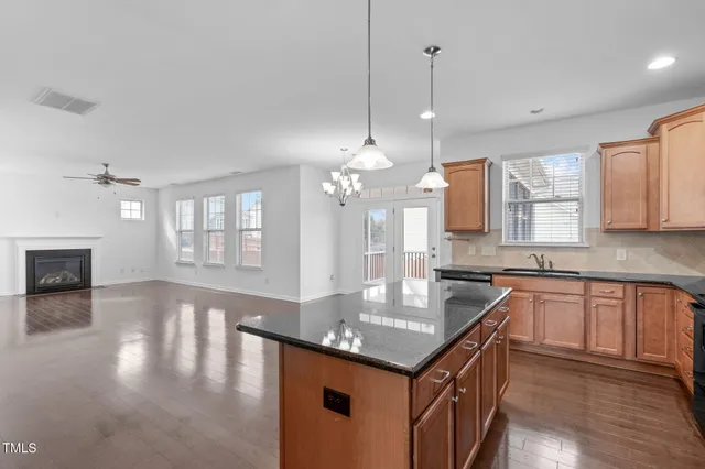 a kitchen with granite countertop a sink cabinets and wooden floor