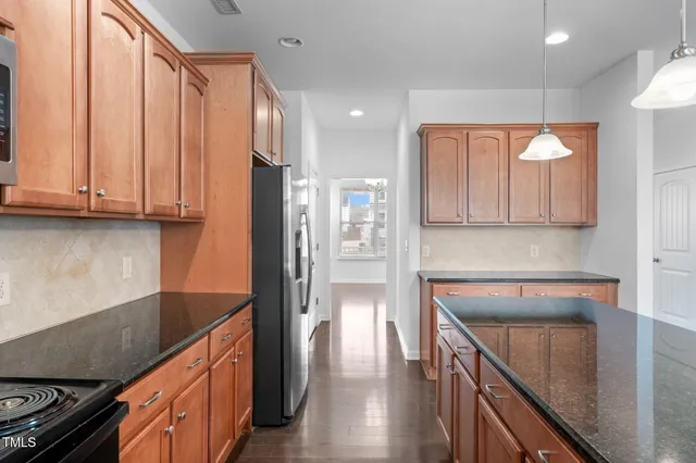 a kitchen with stainless steel appliances granite countertop a refrigerator a sink dishwasher and wooden cabinets with wooden floor