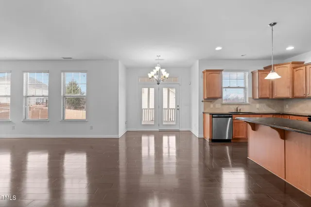 a large kitchen with granite countertop a stove a sink wooden floor dining table and chairs