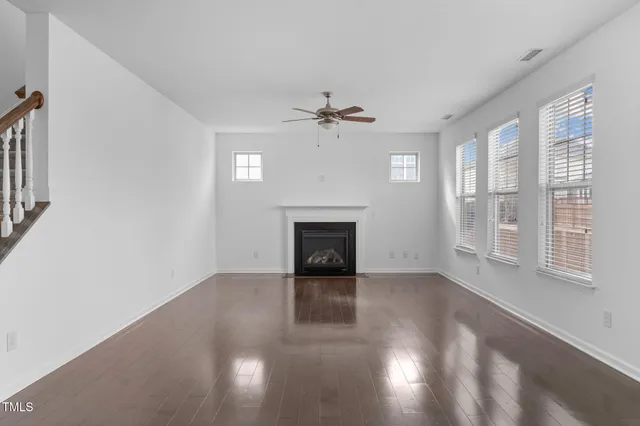 a view of a livingroom with a fireplace a ceiling fan and windows