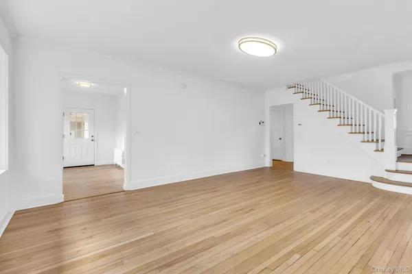 a view of an empty room with wooden floor and stairs