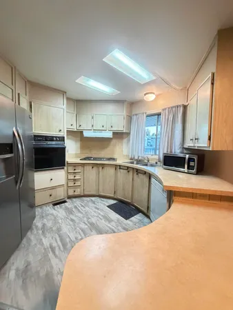 a kitchen with stainless steel appliances a table chairs and microwave
