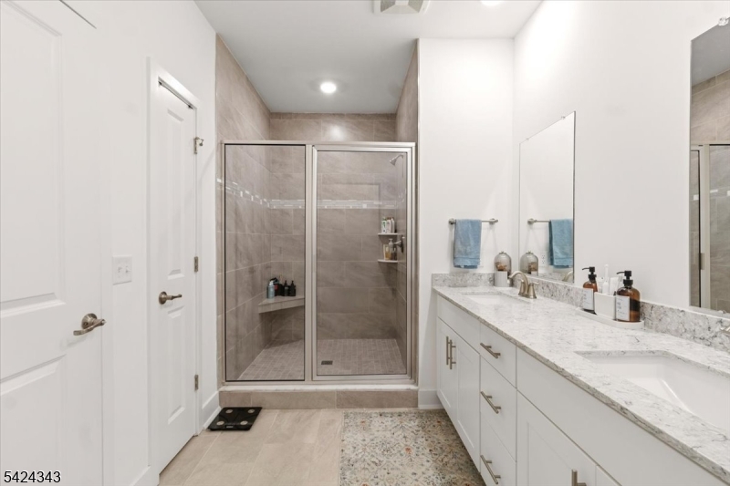 11 Veterans Way, Unit 111 Morris Plains, NJ 07950 - Photo 19 of 21 a bathroom with a granite countertop double vanity sink a mirror and a shower