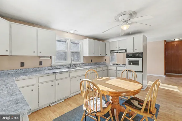 a kitchen with stainless steel appliances granite countertop a sink a stove a refrigerator with a dining table and chairs