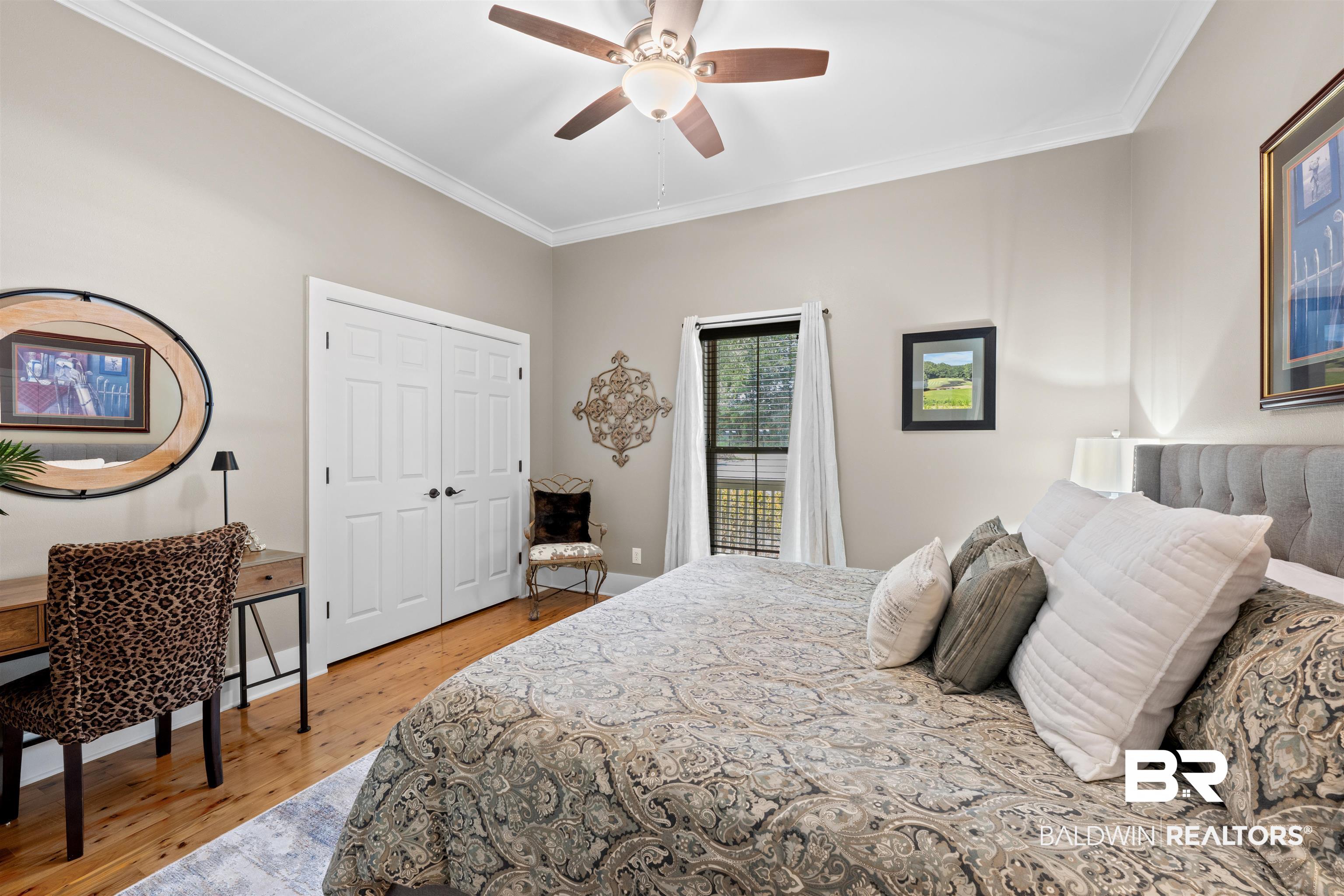 32700 Steelwood Ridge Road, Unit D Loxley, AL 36551 - Photo 18 of 41 Bedroom featuring wood-finish flooring, a ceiling fan, crown molding, a window with blinds, and white bi-fold closet doors