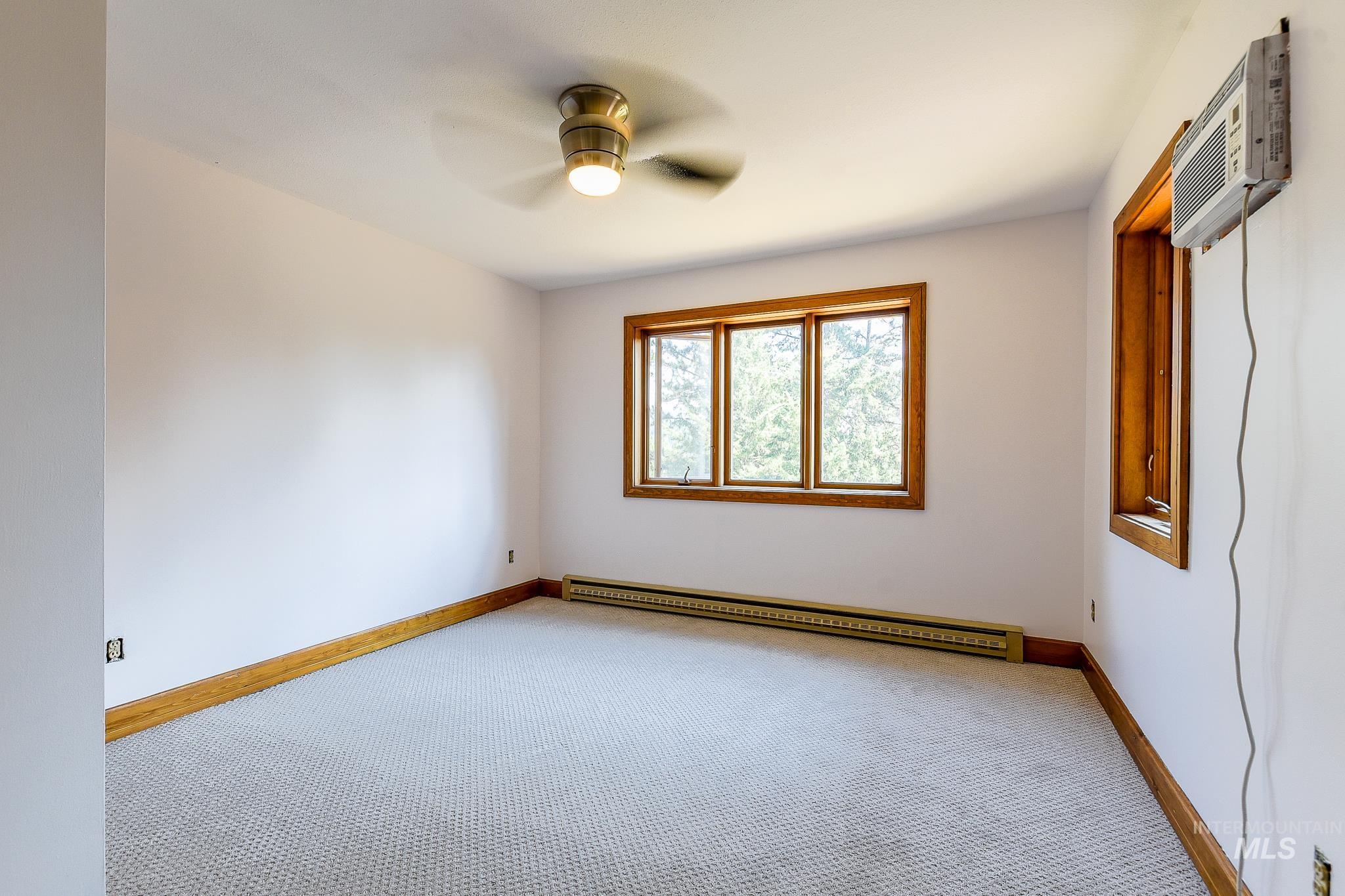 1045 Joyce Road Moscow, ID 83843 - Photo 18 of 50 Neutral tone wall finish, wood-finish window trim, carpeted flooring, and a ceiling fan with integrated lighting