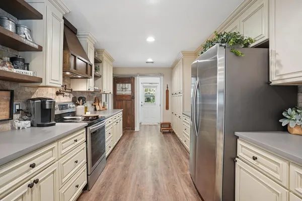 a kitchen with stainless steel appliances granite countertop a refrigerator a stove and a wooden floors