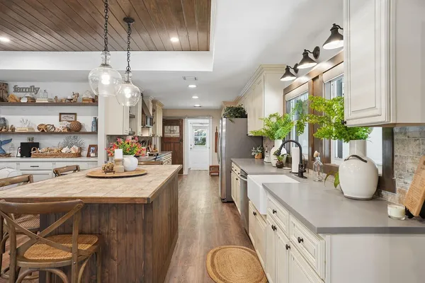 a kitchen with kitchen island granite countertop a white cabinets and chandelier