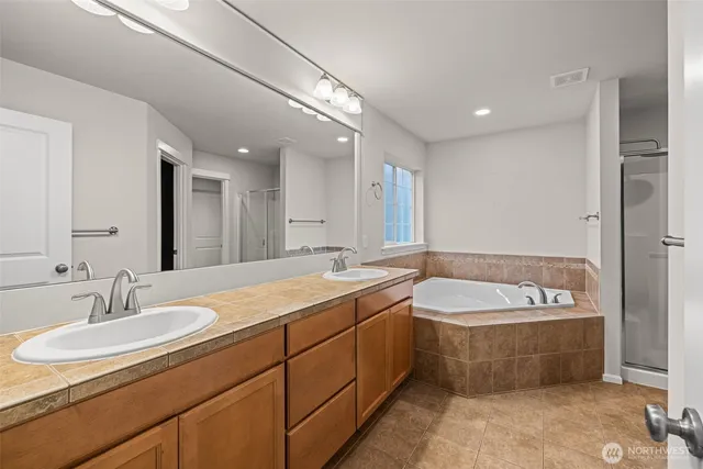a bathroom with a double vanity sink mirror and bathtub