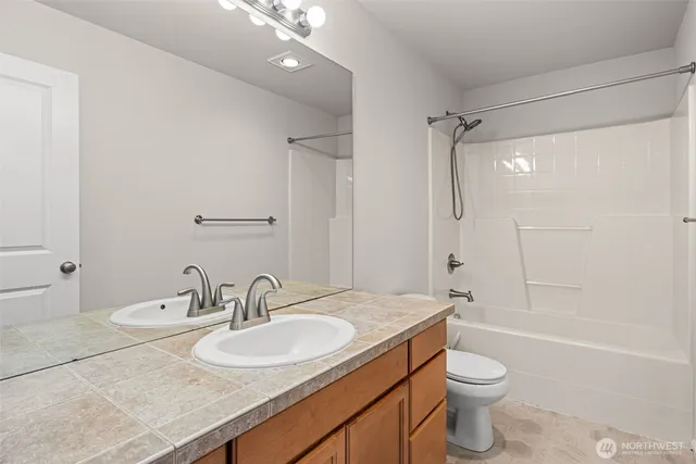 a bathroom with a granite countertop sink a toilet and shower