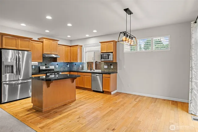 a kitchen with granite countertop a refrigerator and a stove top oven
