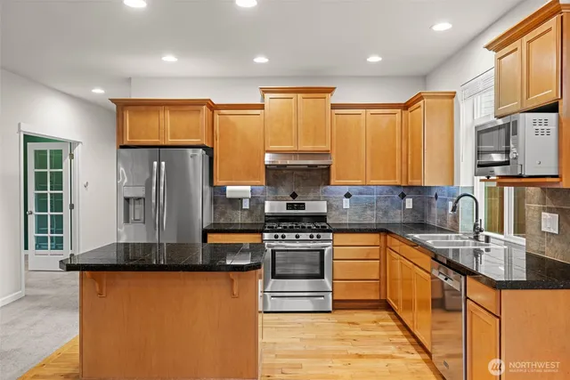 a kitchen with stainless steel appliances granite countertop a refrigerator a stove top oven a sink and dishwasher