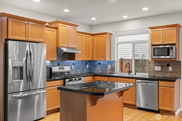 a kitchen with stainless steel appliances granite countertop a sink stove and refrigerator