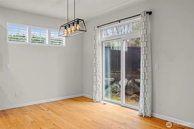 a view of an empty room with glass door and wooden floor