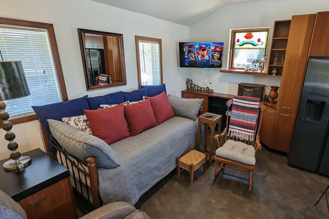 a bedroom with a bed a mirror on the dresser and a chandelier